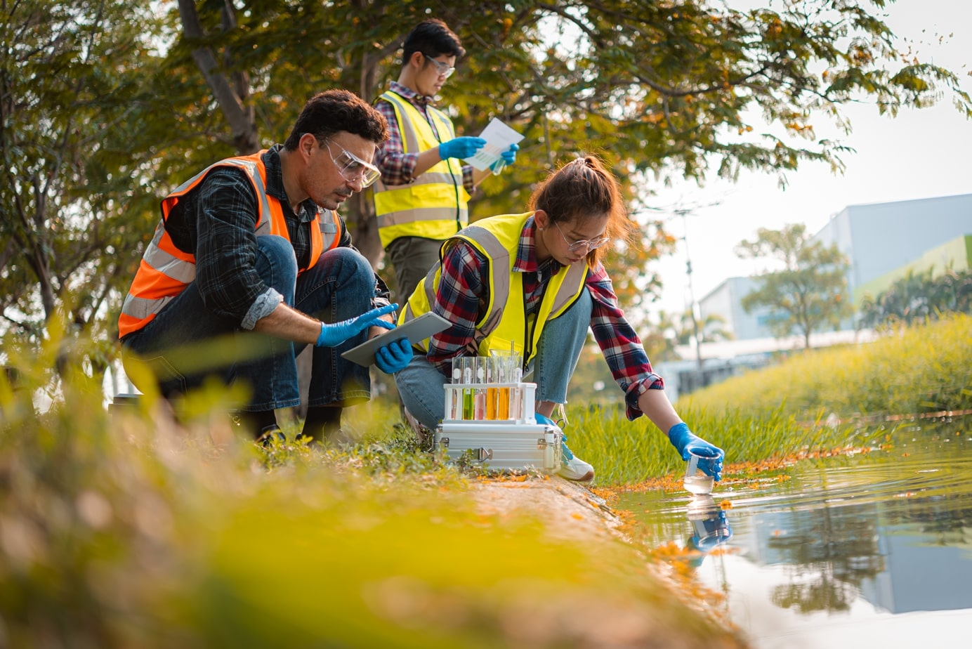 Environmental science scientists collecting water samples outside and using STARLIMS software on a mobile tablet